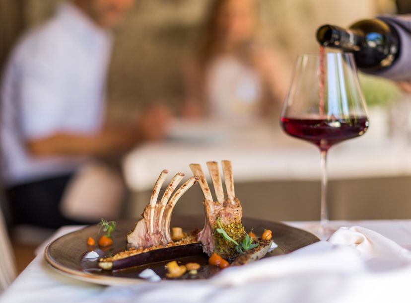 In a fine dining restaurant a glass of red wine is being poured