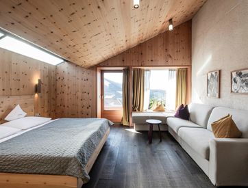 Das Schlafzimmer der Ferienwohnung Santner 1929 mit Doppelbett, großer Couch und Balkon