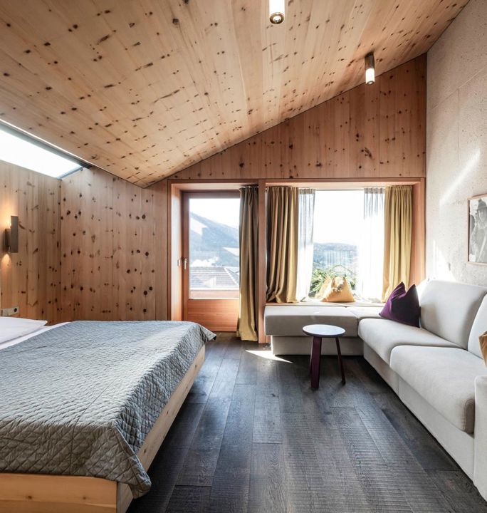 Das Schlafzimmer der Ferienwohnung Santner 1929 mit Doppelbett, großer Couch und Balkon